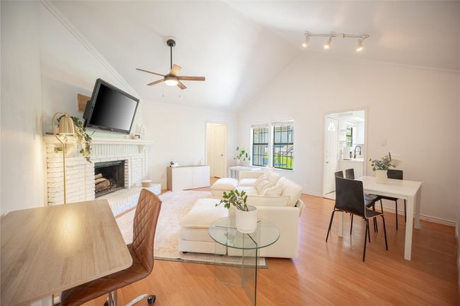 Living room featuring high vaulted ceiling, a ceiling fan, light wood-type flooring, a fireplace, and ornamental molding | Image 6