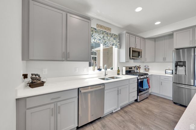 Kitchen featuring appliances with stainless steel finishes, gray cabinets, recessed lighting, and light wood-type flooring | Image 7