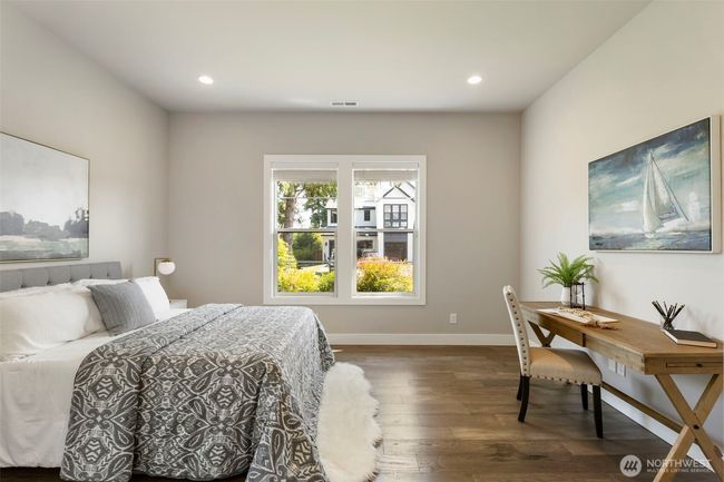 Located on the main level, this spacious guest bedroom offers a peaceful retreat with large windows, hardwood floors, and plenty of natural light. Whether used for visitors or as a private home office, the flexible layout provides comfort and quiet versatility. | Image 23