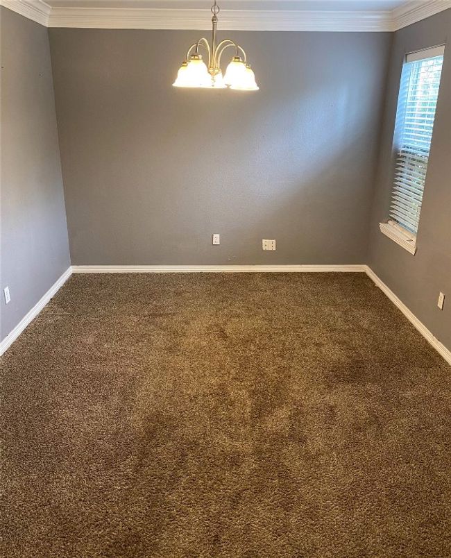 Spare room with baseboards, crown molding, carpet floors, and an inviting chandelier | Image 7