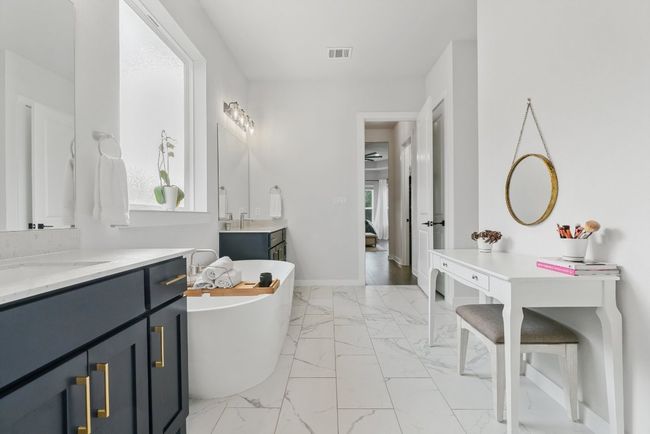 Full bath featuring marble look tiles, two vanities, a freestanding bath, and ensuite bathroom | Image 24