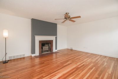 Unfurnished living room featuring ceiling fan, light hardwood / wood-style floors, and a brick fireplace | Image 3