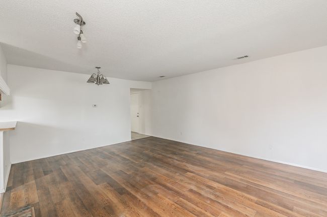 Spare room with wood finished floors, a chandelier, track lighting, and a textured ceiling | Image 5