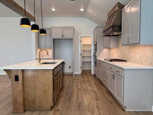 Kitchen with custom range hood, backsplash, a sink, gas cooktop, and lofted ceiling | Image 9