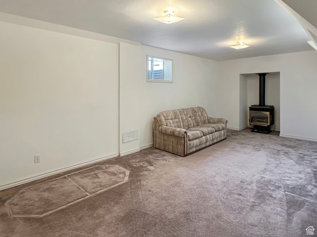 Living area with a wood stove, carpet floors, and baseboards | Image 21