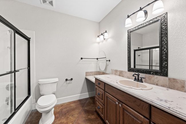 Full bath featuring vanity, toilet, baseboards, concrete floors, and combined bath / shower with glass door | Image 31