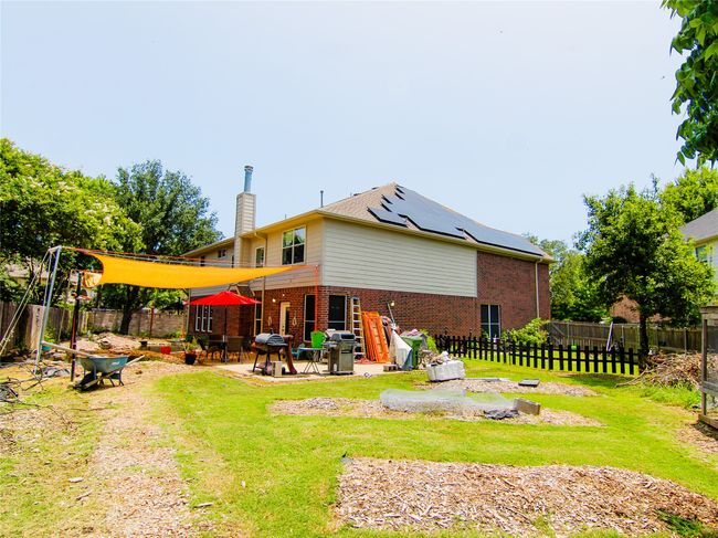 Back of property with brick siding, solar panels, a chimney, and a patio area | Image 12