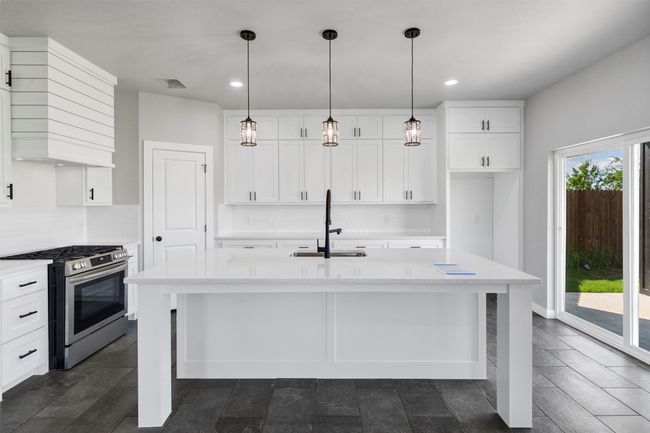 Kitchen with stainless steel gas stove, a sink, wall chimney exhaust hood, white cabinetry, and recessed lighting | Image 13