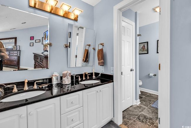 Bathroom featuring double vanity, toilet, baseboards, and a sink | Image 21