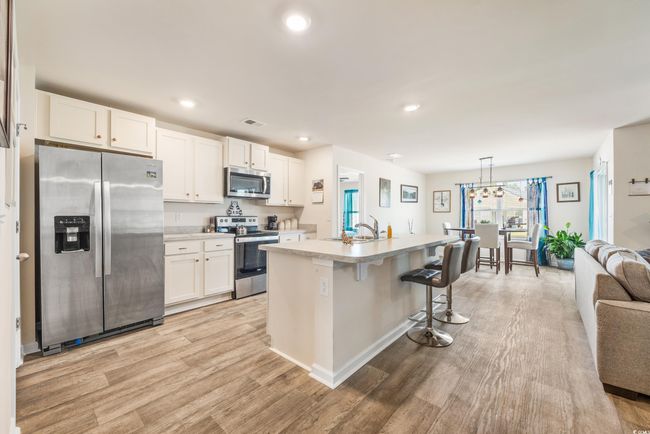 Kitchen with stainless steel appliances, white cabinetry, light wood finished floors, open floor plan, and recessed lighting | Image 14