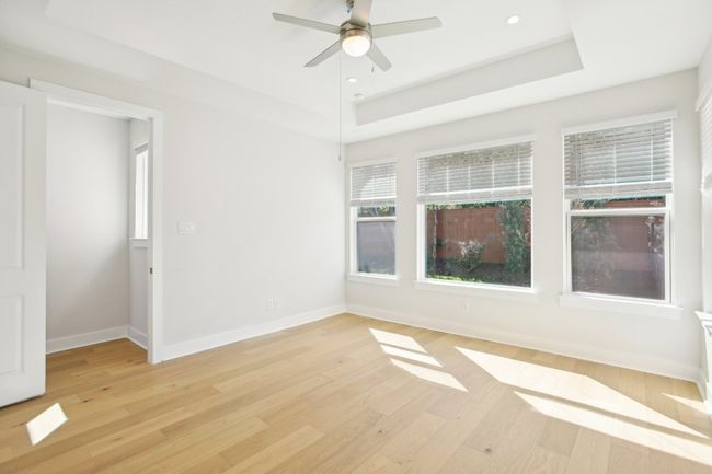 Unfurnished room featuring light wood-style flooring, a raised ceiling, baseboards, and a ceiling fan | Image 10