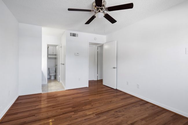 Bedroom with ensuite bathroom, a textured ceiling, and wood finished floors | Image 18