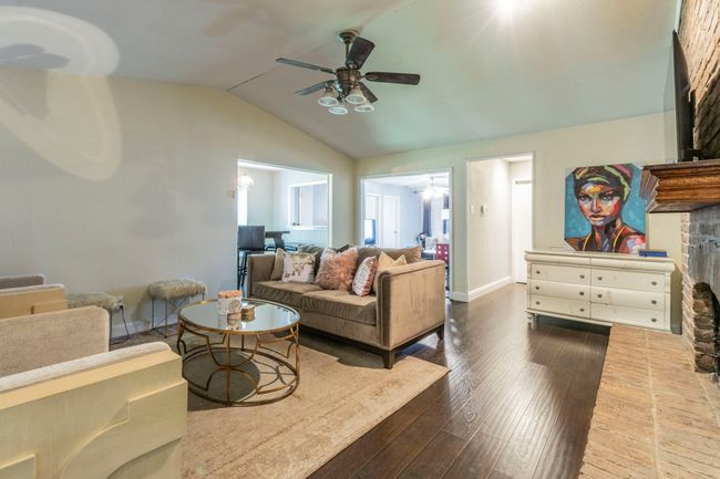 Living area with ceiling fan, vaulted ceiling, hardwood / wood-style floors, baseboards, and a fireplace | Image 5