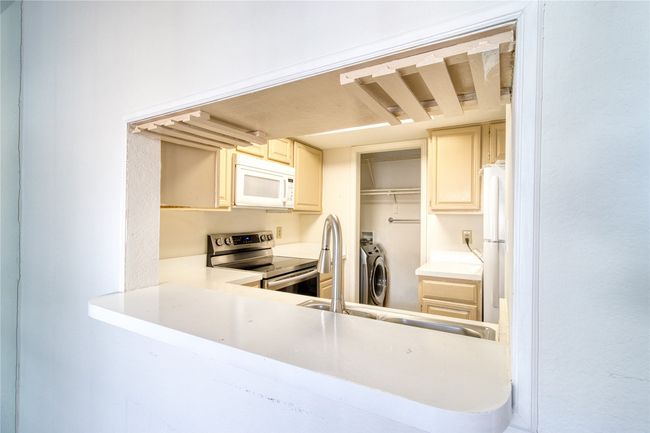 Kitchen with white appliances, independent washer and dryer, light countertops, and cream cabinetry | Image 15