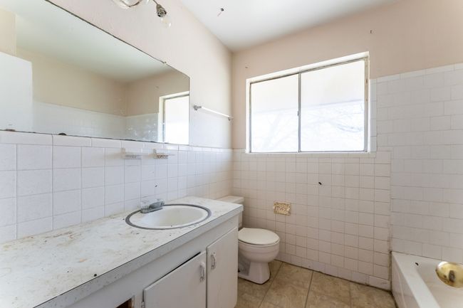 Full bath featuring tile patterned flooring, tile walls, toilet, a bathtub, and vanity | Image 5