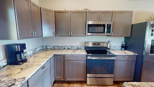 Kitchen featuring light stone countertops, wood finished floors, and stainless steel appliances | Image 7