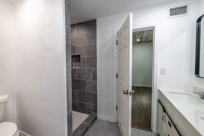 Bathroom featuring double vanity, walk in shower, toilet, visible vents, and a sink | Image 14