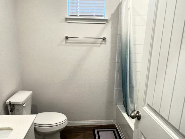 Bathroom with baseboards, vanity, toilet, wood finished floors, and shower / tub combo | Image 14