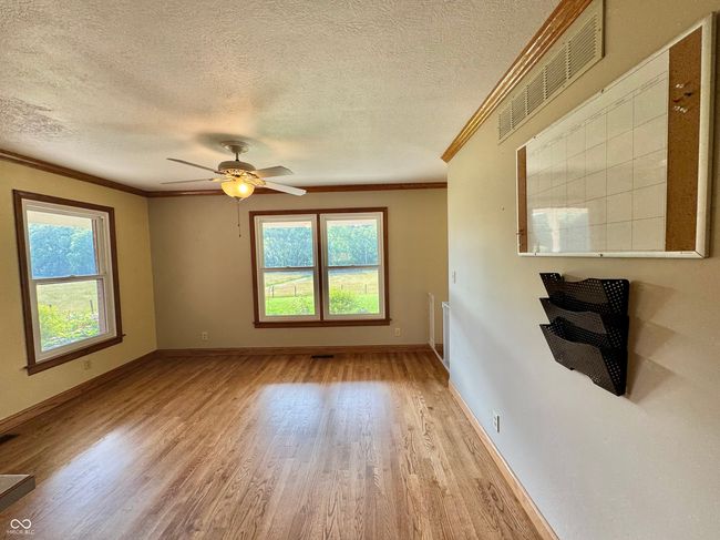 unfurnished living room featuring crown molding, light wood-style floors, a textured ceiling, baseboards, and a ceiling fan | Image 45