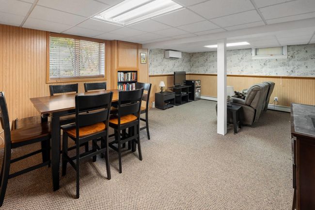 Carpeted dining area with a drop ceiling, wooden walls, a wall mounted AC, and baseboard heating | Image 10