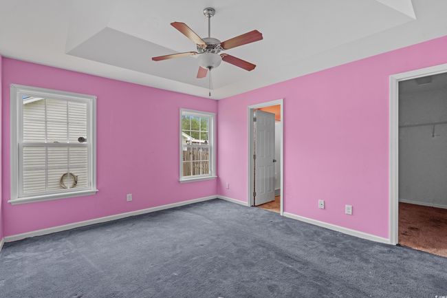 Unfurnished bedroom featuring carpet floors, baseboards, a spacious closet, and a tray ceiling | Image 28
