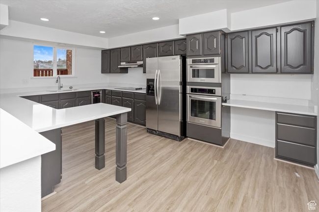 Kitchen with recessed lighting, under cabinet range hood, a sink, light wood-style floors, and appliances with stainless steel finishes | Image 7