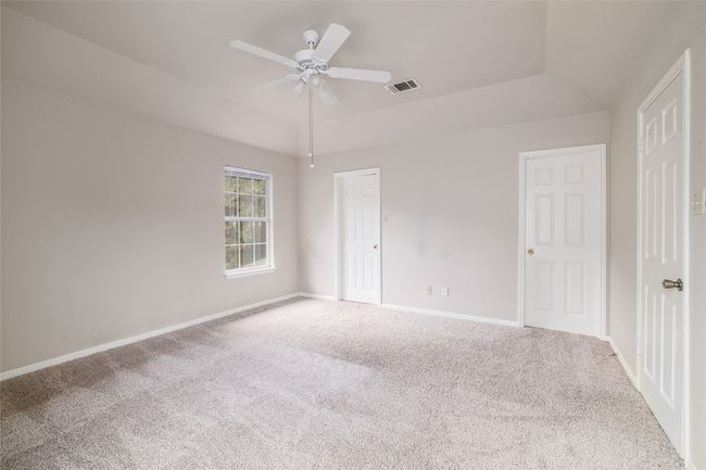 Unfurnished bedroom with carpet floors, lofted ceiling, baseboards, and a ceiling fan | Image 12