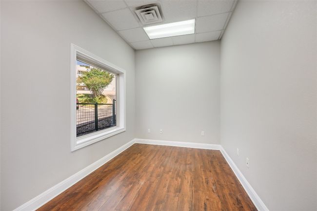 Unfurnished room featuring dark wood finished floors, a paneled ceiling, visible vents, and baseboards | Image 12