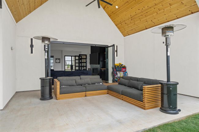 Living room with high vaulted ceiling, a ceiling fan, and wood ceiling | Image 35