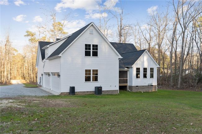 Rear view of property with a garage, a lawn, gravel driveway, crawl space, and central AC unit | Image 47