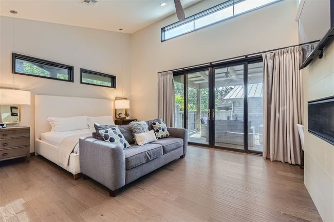 Bedroom featuring a high ceiling, wood finished floors, visible vents, and access to exterior | Image 5