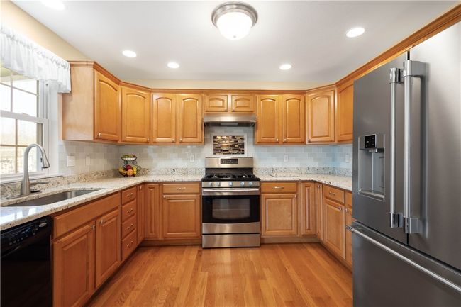 Maple cabinets, granite counters and a glass tiled backsplash highlight the kitchen. | Image 9