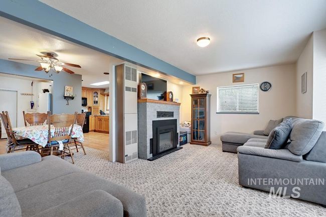 Carpeted living area featuring a glass covered fireplace and ceiling fan | Image 9