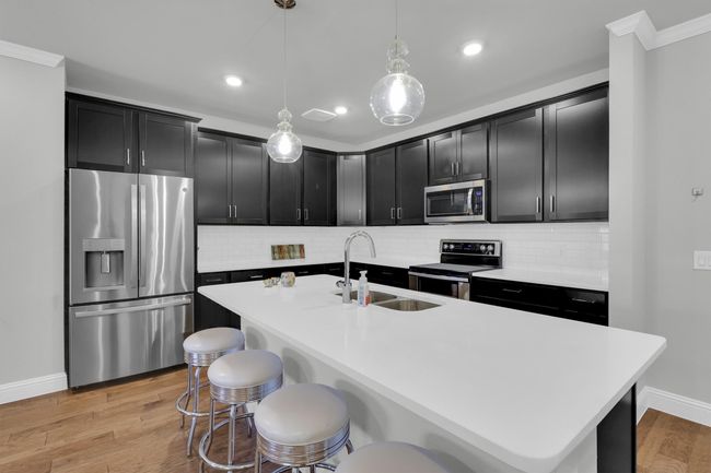 Kitchen featuring stainless steel appliances, a sink, dark cabinets, crown molding, and a kitchen breakfast bar | Image 4