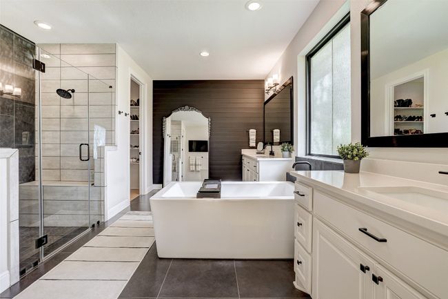 Primary bathroom with a walk in closet, two vanities, shower, a freestanding bath, and tile flooring | Image 15
