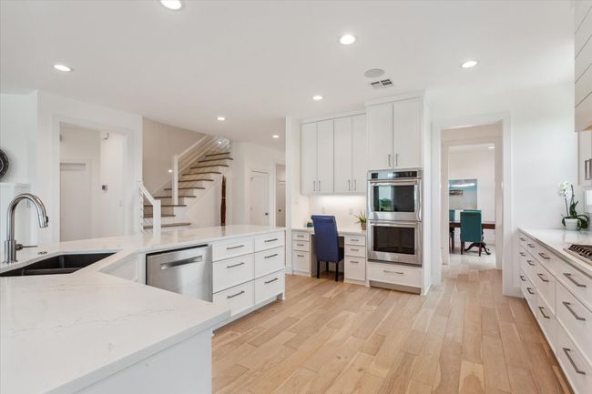 Kitchen with stainless steel appliances, a sink, light wood-type flooring, recessed lighting, and white cabinets | Image 14