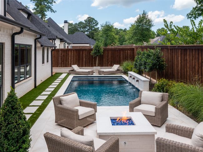 View of pool featuring an outdoor living space with a fire pit, a patio area, and a fenced backyard | Image 34