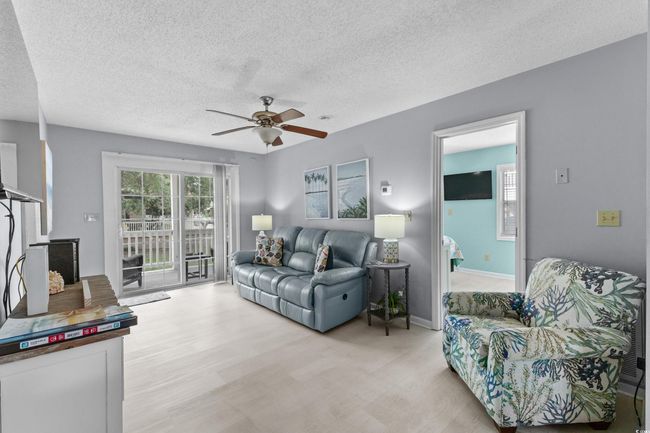 Living room featuring a ceiling fan, a textured ceiling, baseboards, and light wood finished floors | Image 5
