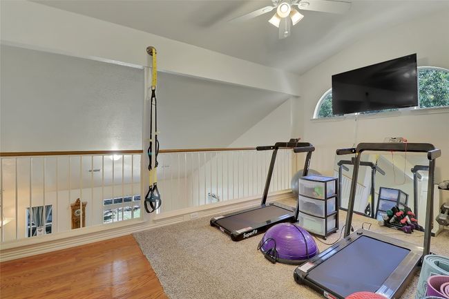 Exercise room with vaulted ceiling, ceiling fan, plenty of natural light, and wood finished floors | Image 19