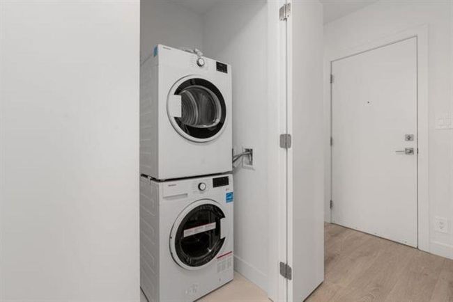 Washroom with laundry area, stacked washer and clothes dryer, and light wood finished floors | Image 16