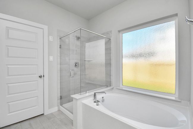 Indulge in a spa-like retreat within the confines of this primary bathroom. Delight in a spacious walk-in shower enveloped in stylish tile surround and unwind in a separate garden tub adorned with custom detailing. | Image 27