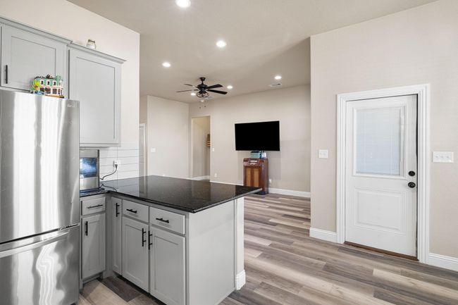 Kitchen with recessed lighting, light wood-style flooring, decorative backsplash, freestanding refrigerator, and a peninsula | Image 15