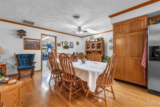 Dining area with ceiling fan, light wood-style flooring, and crown molding | Image 64