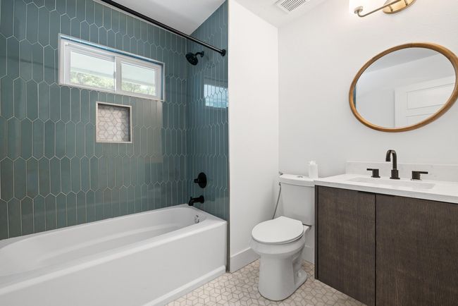 Bathroom with tile patterned floors, bathing tub / shower combination, toilet, visible vents, and vanity | Image 25