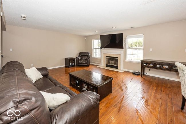 living area featuring recessed lighting, visible vents, wood-type flooring, baseboards, and a tiled fireplace | Image 5