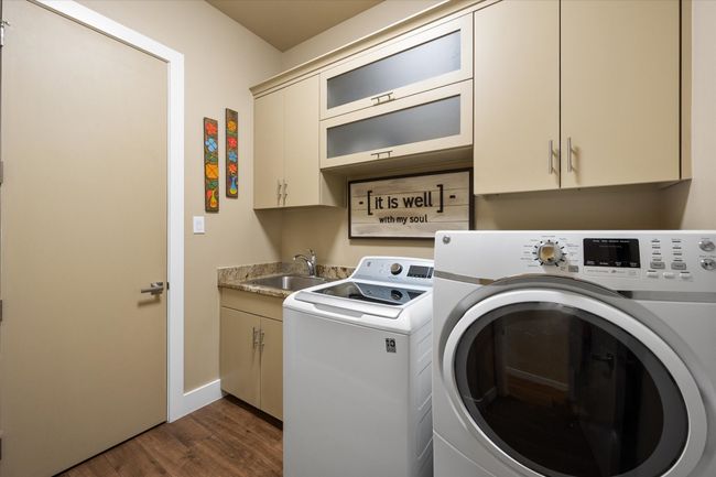 Utility room has a sink, washer and dryer hook ups with upper and lower cabinets. | Image 22