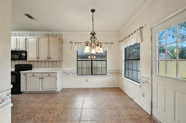 Kitchen featuring black appliances, a chandelier, crown molding, light countertops, and hanging light fixtures | Image 19