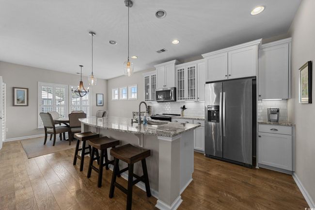 Kitchen featuring appliances with stainless steel finishes, a center island with sink, backsplash, a kitchen bar, and recessed lighting | Image 7