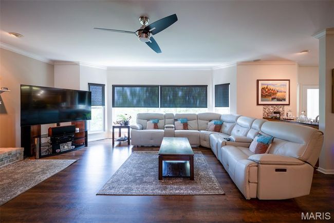 Living room with a ceiling fan, wood finished floors, and crown molding | Image 15