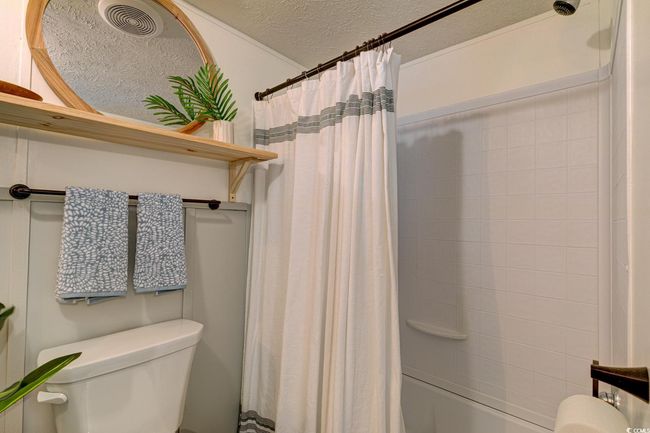 Bathroom featuring toilet, a textured ceiling, and shower / bath combo | Image 19